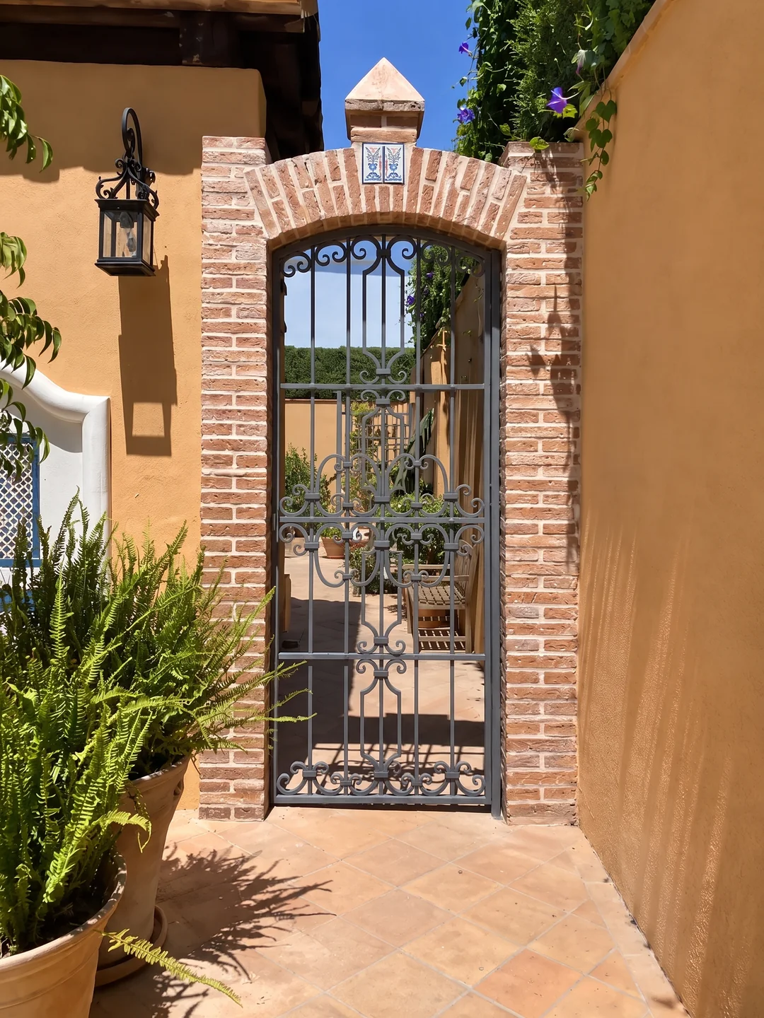 Cancela elegante de forja artesanal en arco de ladrillo rústico para acceso a patio en Sevilla