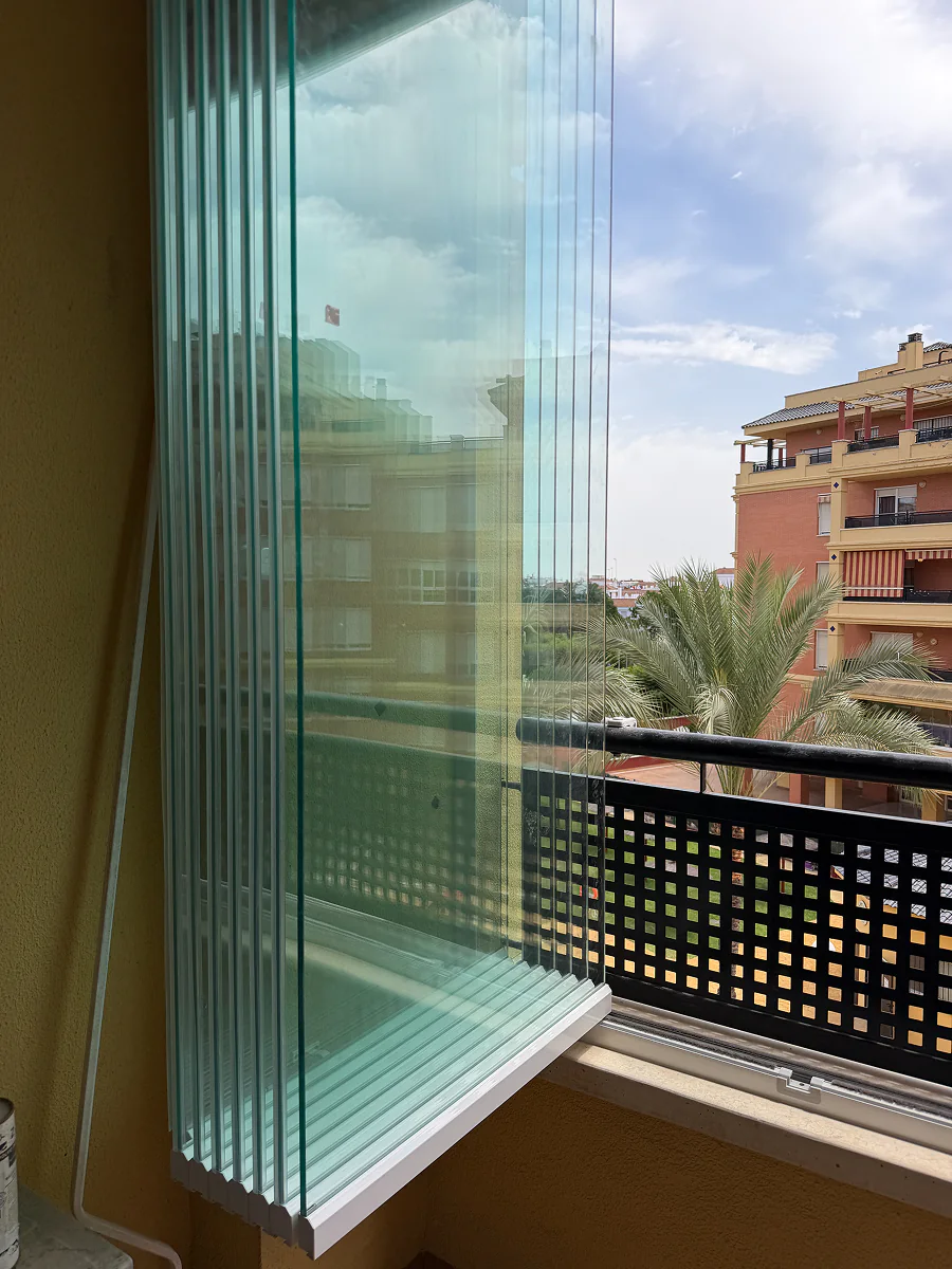Hojas de cristal templado plegadas ocupando mínimo espacio en balcón de Sevilla