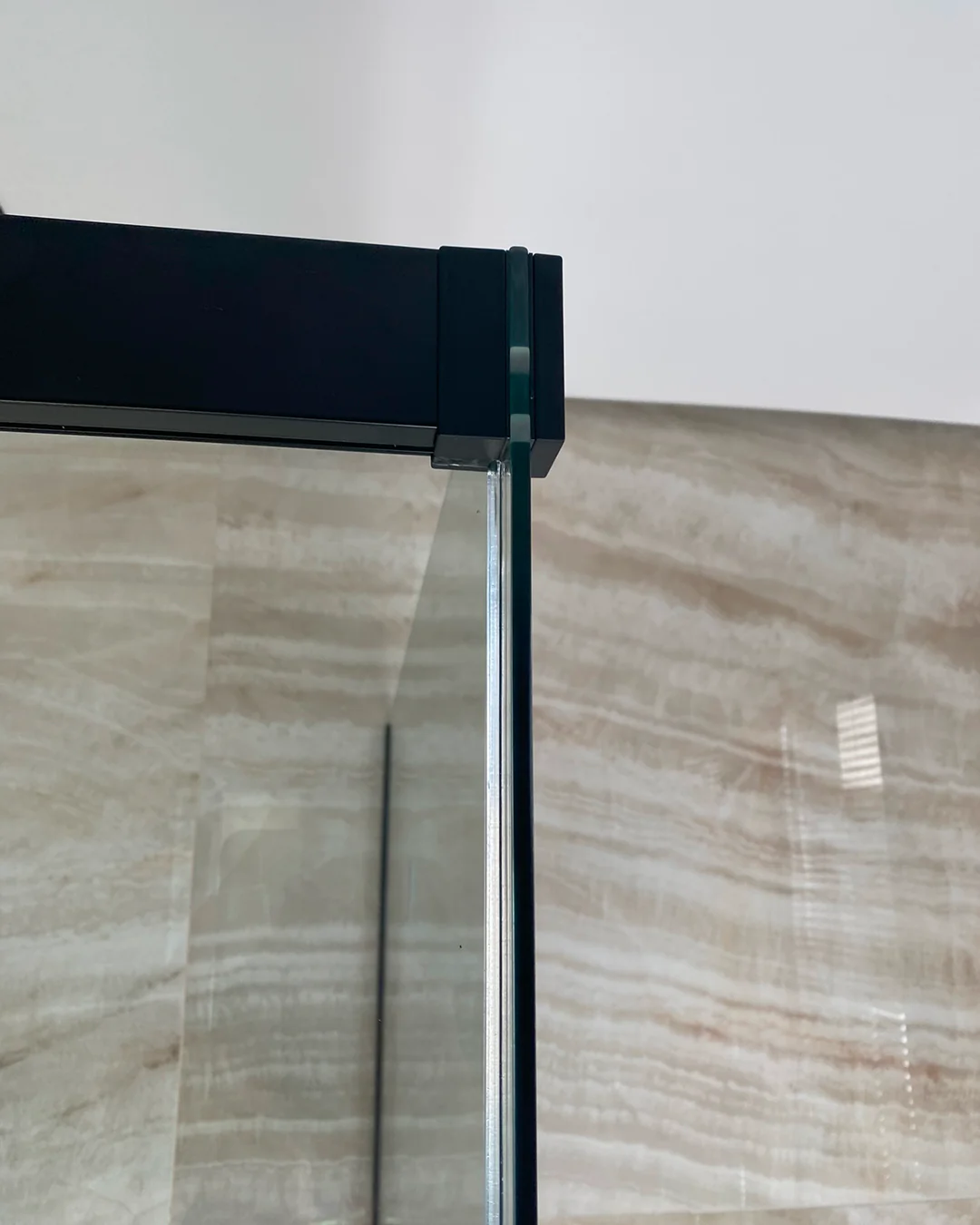 Detalle de perfil de compensación en aluminio negro mate y unión estanca de cristal