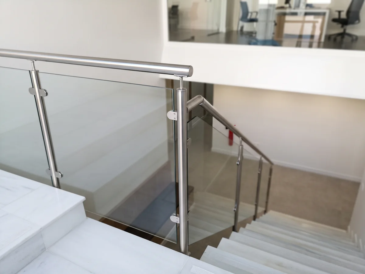 Barandilla de acero inoxidable con pinzas y vidrio para escalera interior en Sevilla