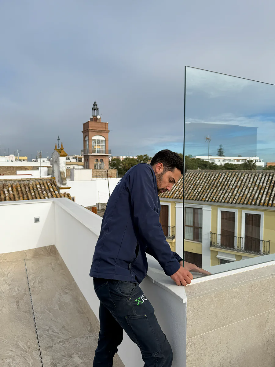 Instalador de SALCOPLUS ajustando panel de vidrio en azotea en La Puebla del Río