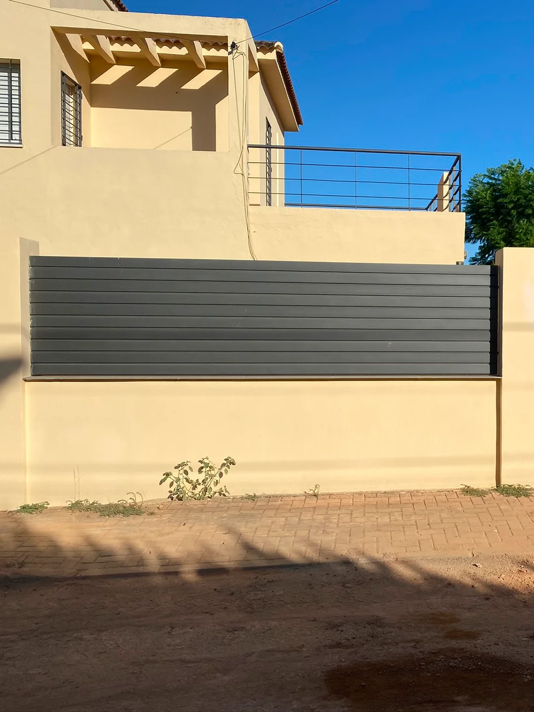 Valla moderna para jardín con panel de lamas horizontales sobre muro perimetral en Sevilla