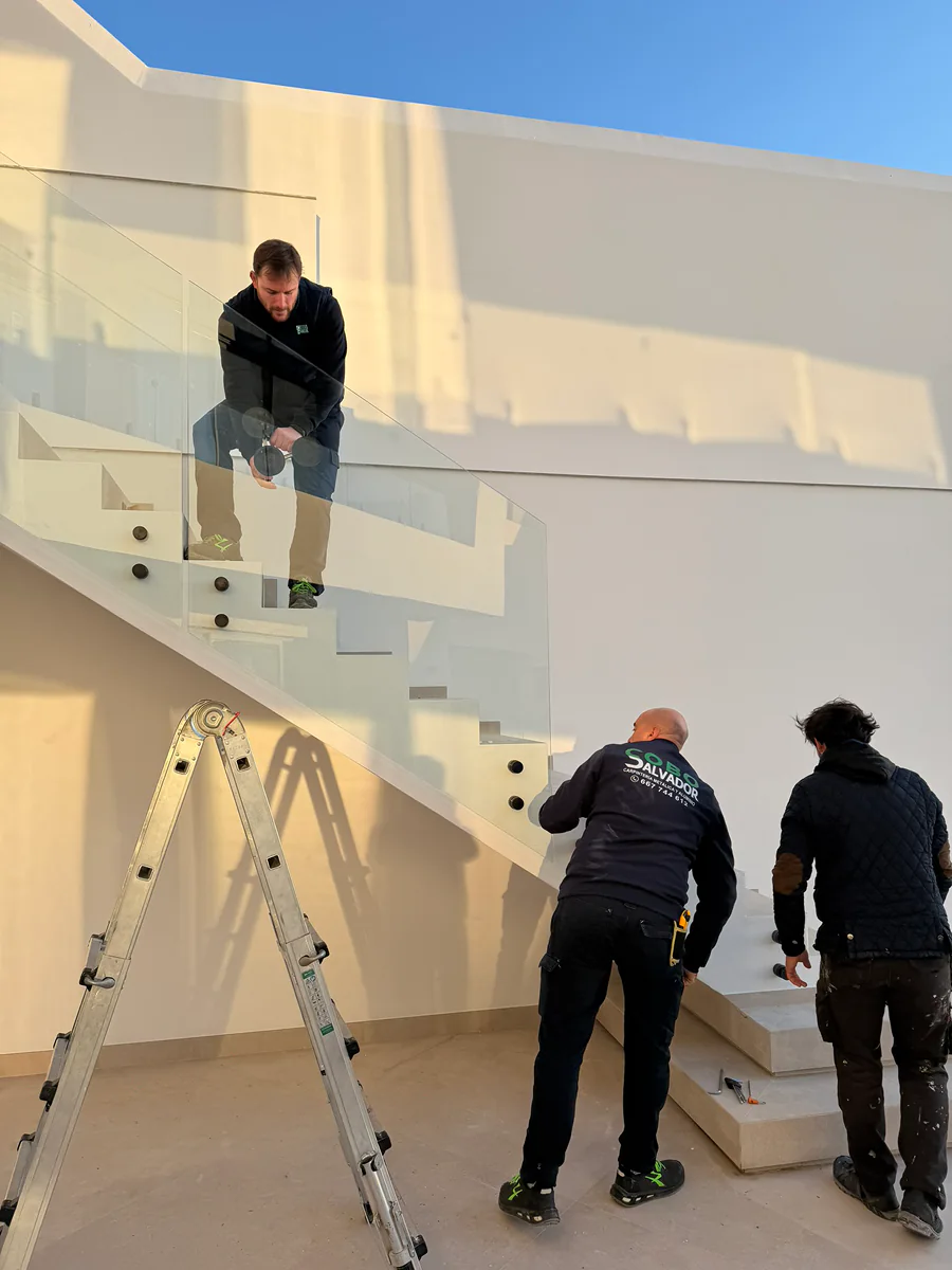 Equipo de SALCOPLUS montando barandilla de vidrio con botones de acero en escalera exterior