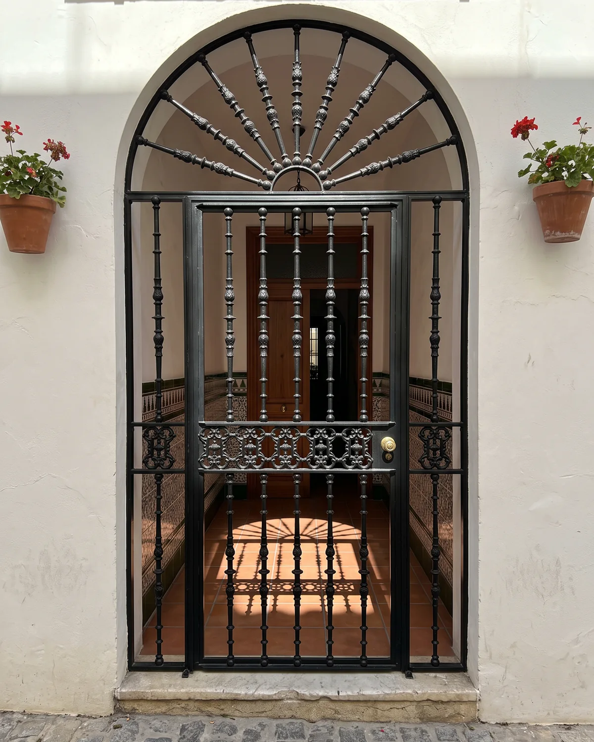 Cancela y portón de hierro en arco con dibujo decorativo en Sevilla
