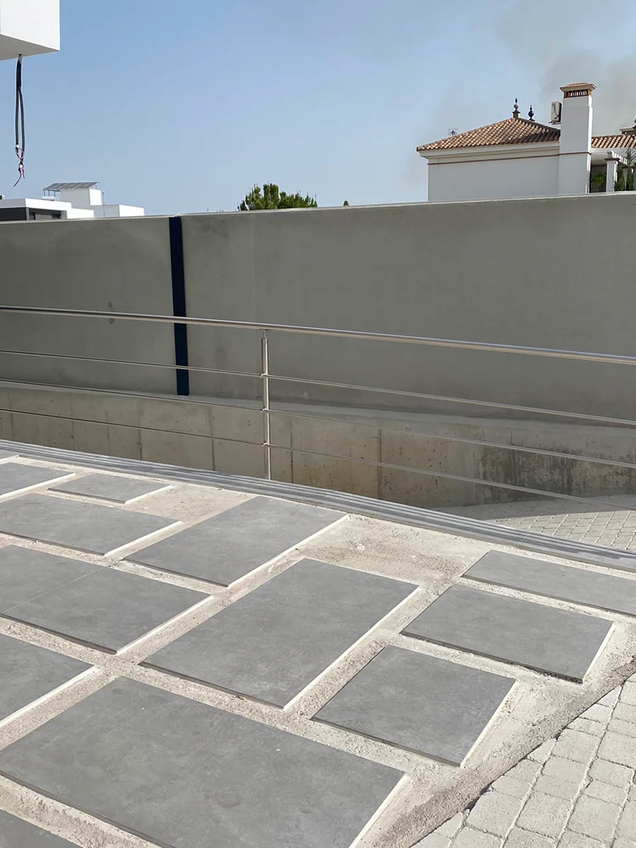 Barandilla de acero inoxidable con varillas horizontales en rampa de acceso en Sevilla