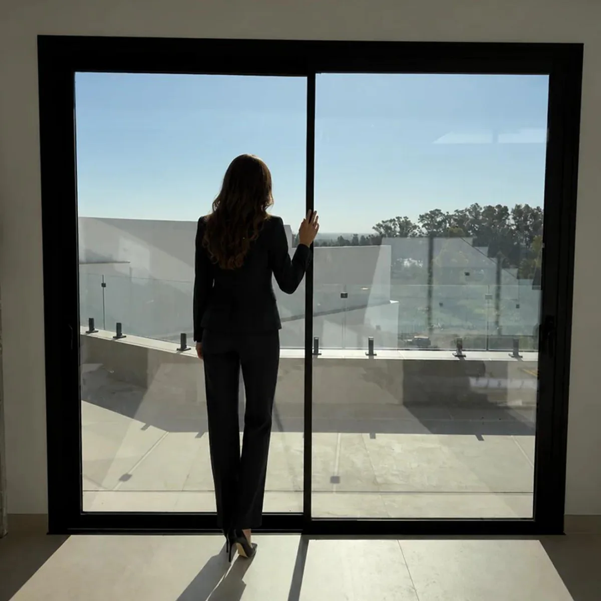 Persona contemplando las vistas a través de un cerramiento de terraza de vidrio a medida en Sevilla