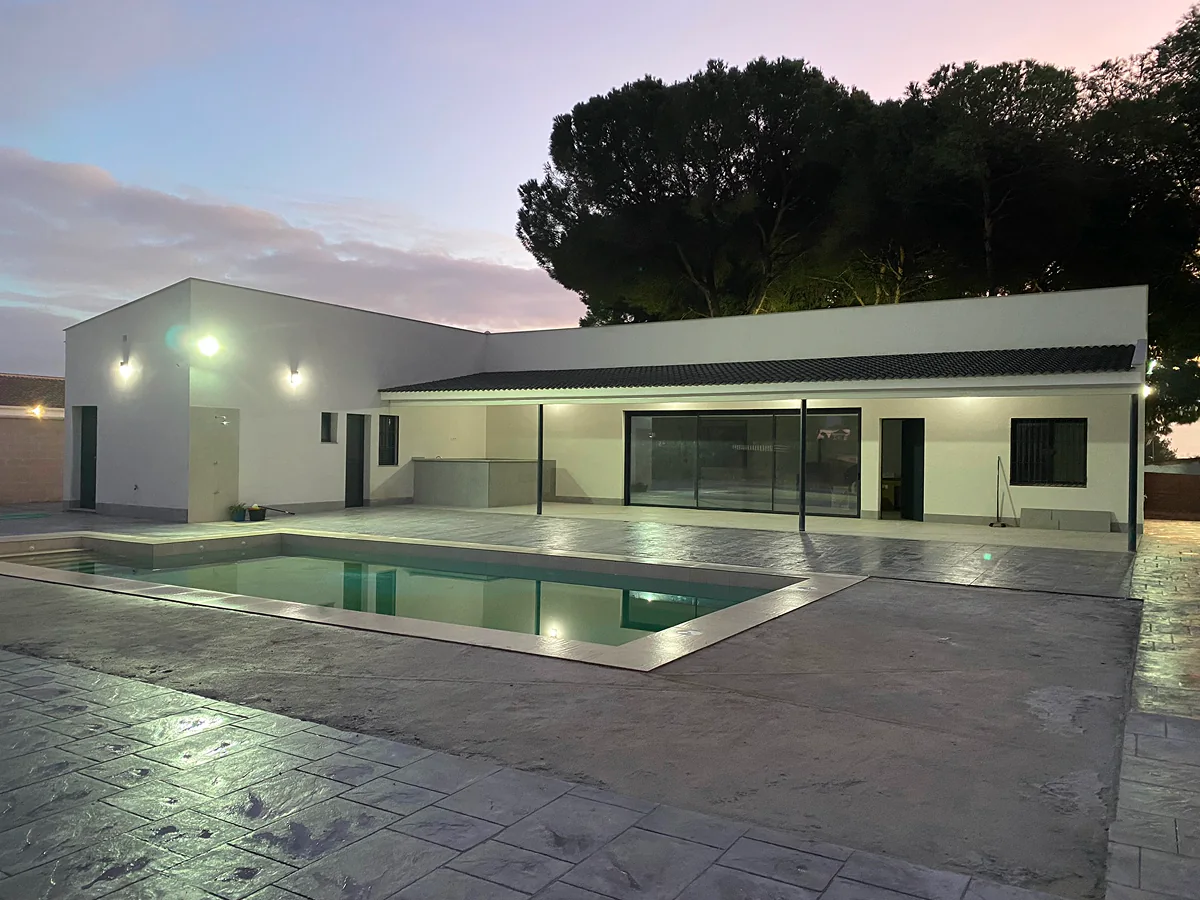 Porche y terraza con cerramiento de aluminio y vidrio junto a piscina en vivienda de Sevilla