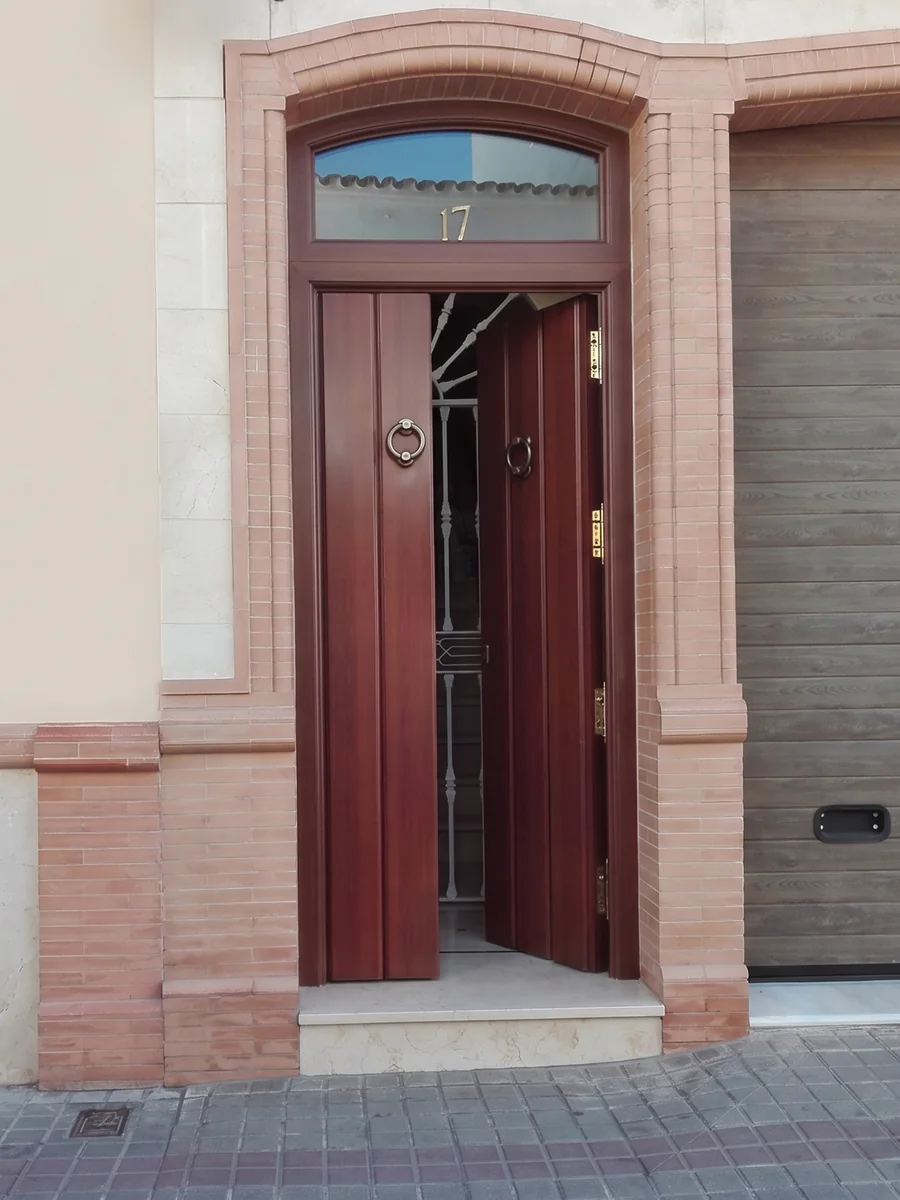 Puerta de portal clásica renovada para comunidad en Sevilla