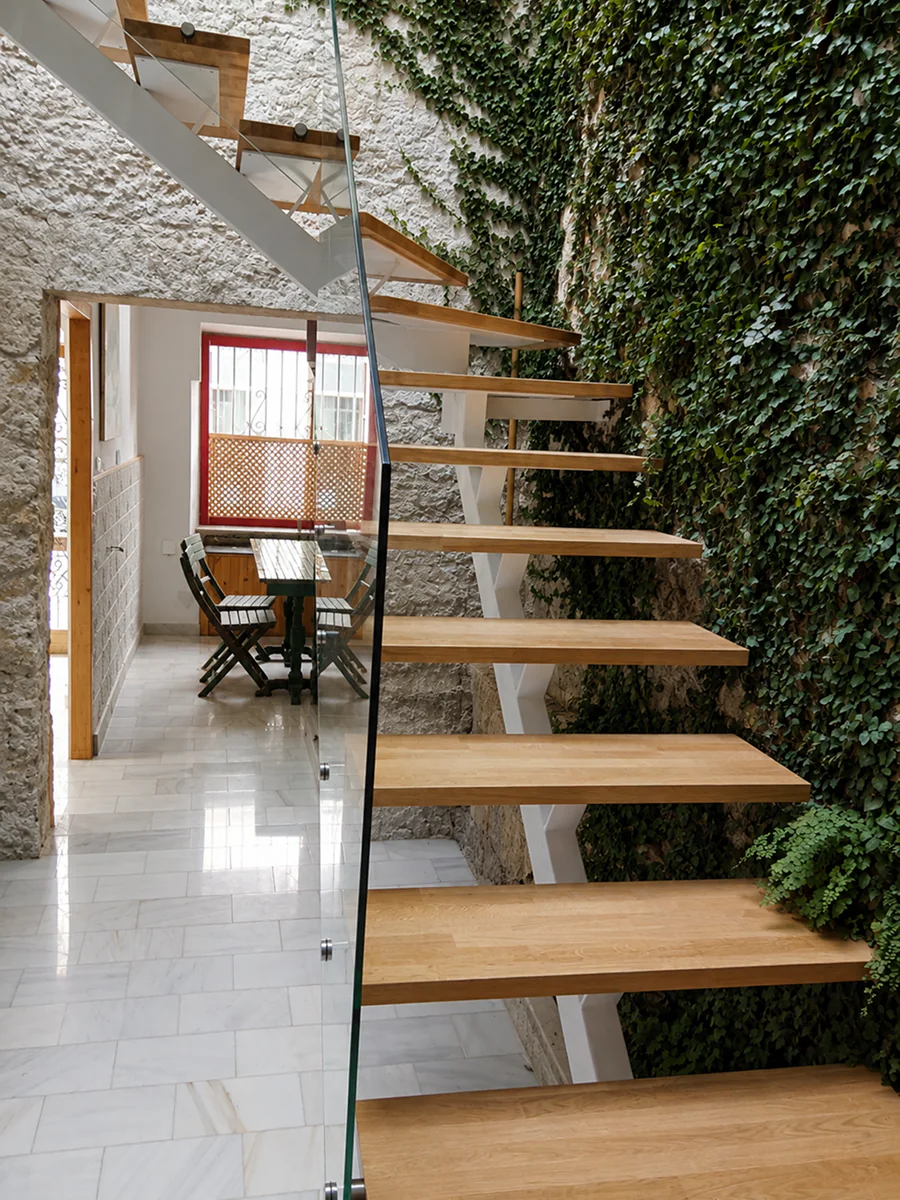 Escalera de zancas en cremallera blanca y peldaños de madera en patio interior · Madera no incluida