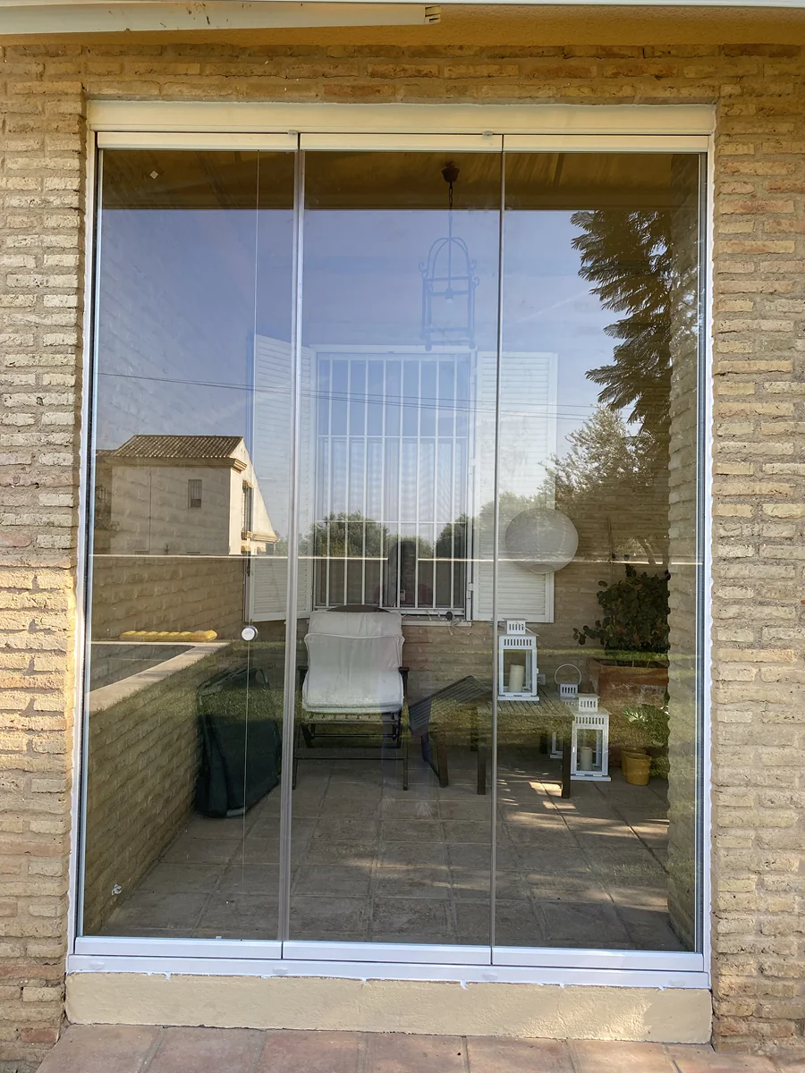 Cerramiento con cortina de cristal de suelo a techo en porche residencial de Sevilla