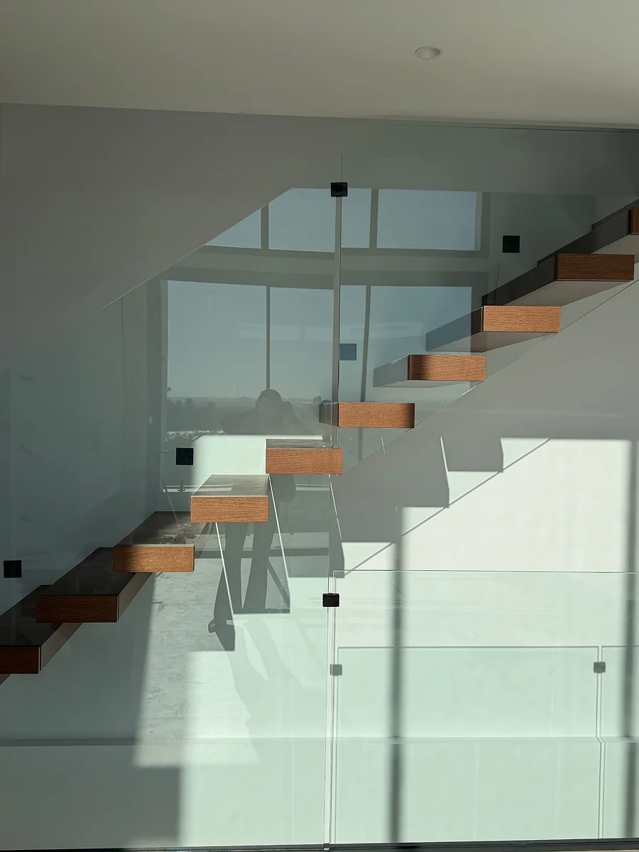 Escalera volada con peldaños flotantes de madera y barandilla de vidrio · Madera no incluida