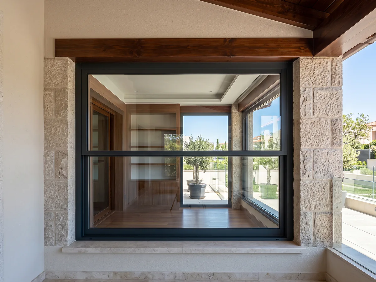 Ventana de guillotina motorizada integrada en porche de piedra y madera en Sevilla