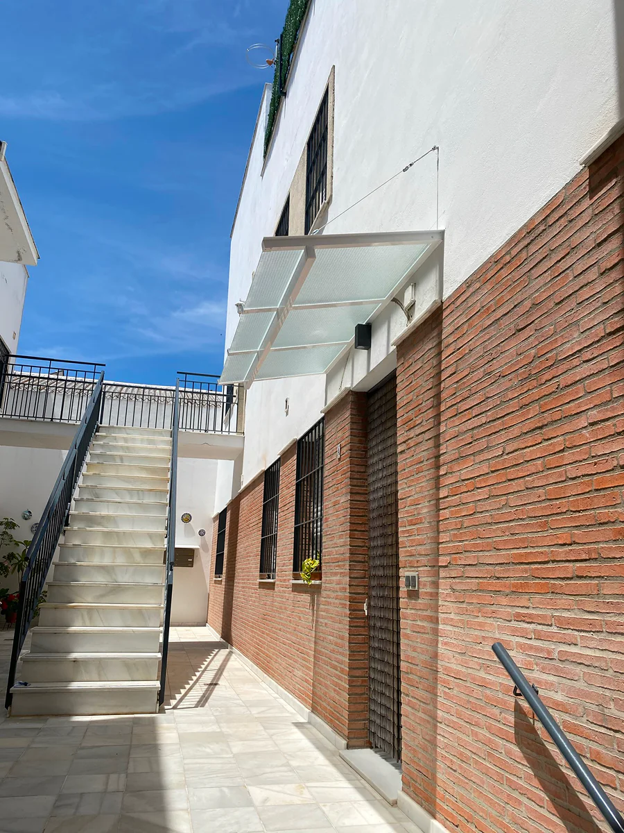 Tejadillo de vidrio suspendido con tirantes de acero inoxidable en patio sevillano